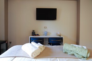 Una habitación de hotel con una cama, dos sillas, un escritorio, un televisor y una cafetera.