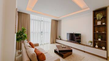 Una sala de estar moderna con un sofá, una mesa de centro, un televisor y una estantería.