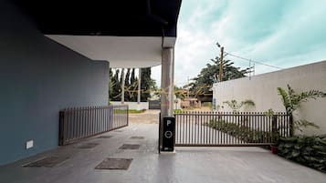 A covered outdoor area with a metal gate, a sign indicating a parking area, and a pathway leading to a building entrance.