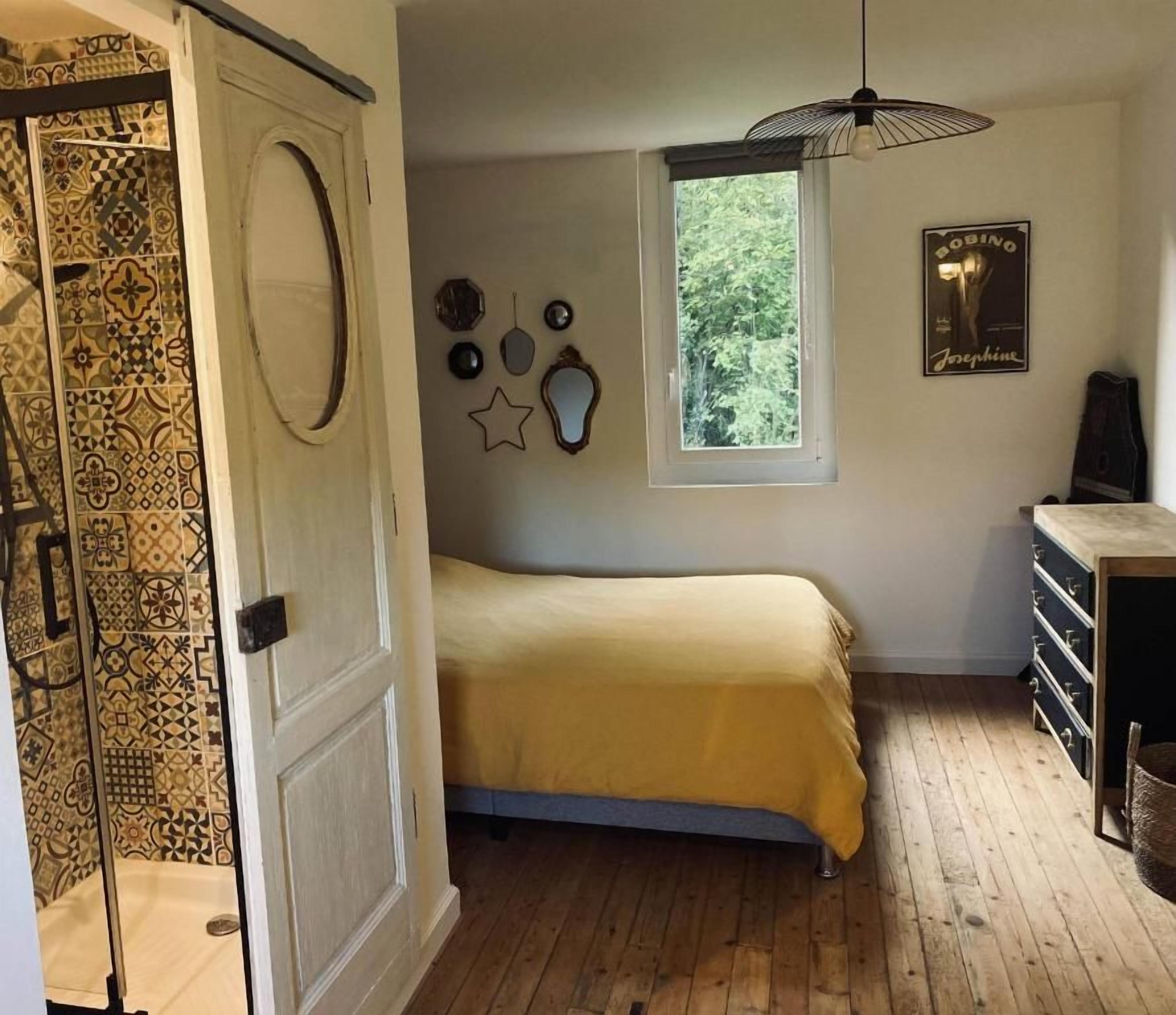 Een slaapkamer met een bed, een raam, een kledingkast en een deur met behang.