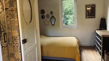 Een slaapkamer met een bed, een raam, een kledingkast en een deur met behang.