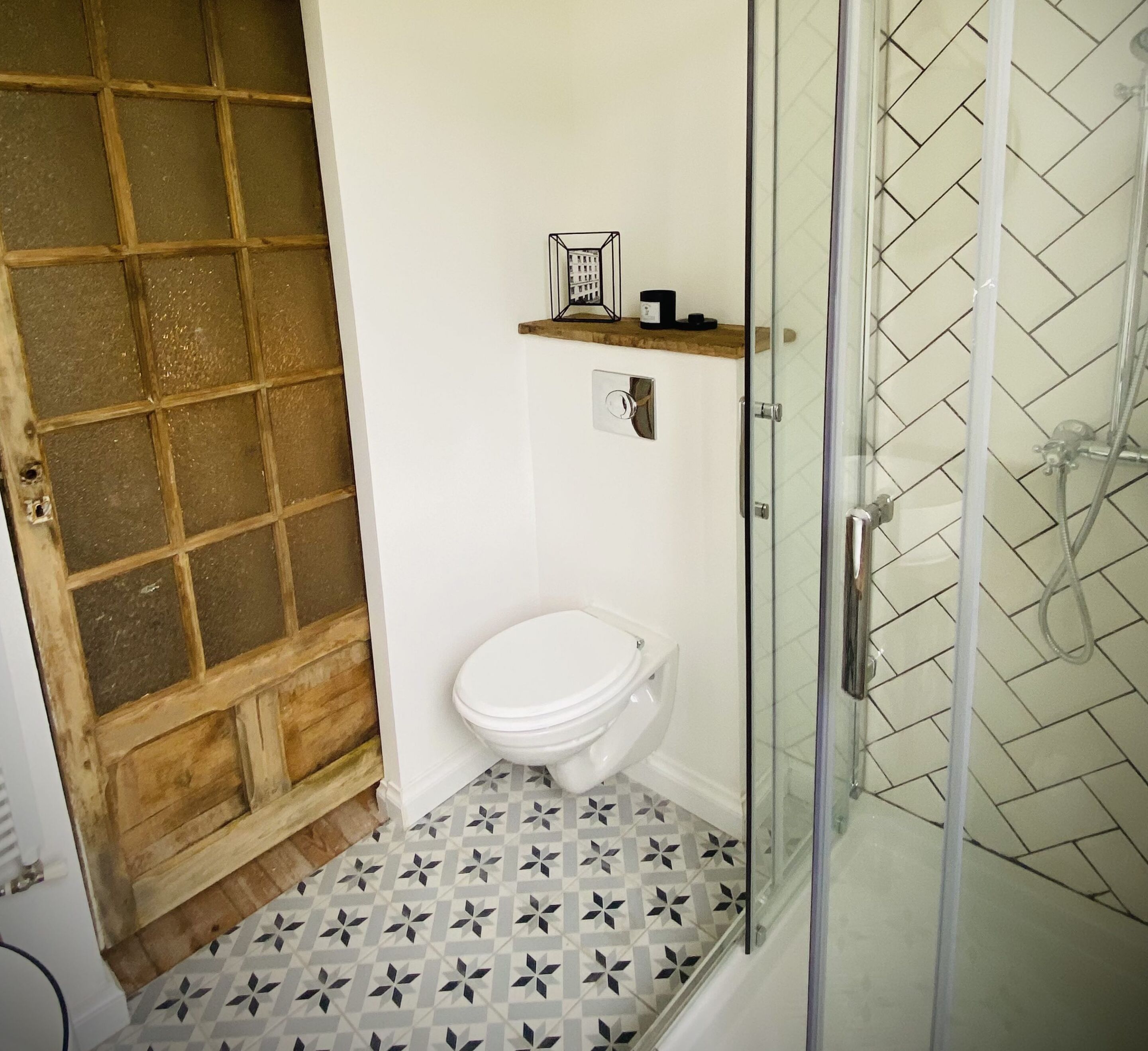Un baño con inodoro, ducha y piso estampado.
