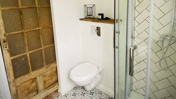 Un baño con inodoro, ducha y piso estampado.