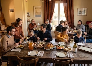 A family dining room with a wooden table set for a meal, surrounded by chairs.