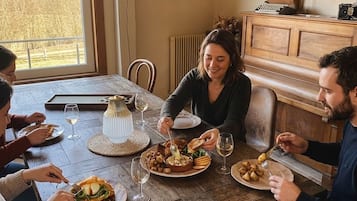 A wooden dining table with plates of food and wine glasses.