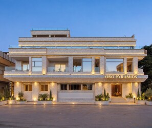 Un hotel de varios pisos con fachada de piedra, balcones y un cartel que dice 'Oro Pyramids'.