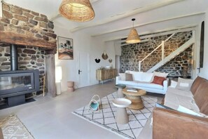 Ein großzügiger Wohnbereich mit Steinwand, Kamin, einer Couch und einer Treppe.