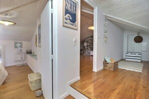 Quarto com piso de madeira, porta branca e pôster emoldurado na parede.