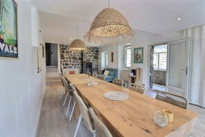 A spacious dining area with a long wooden table, wicker chairs, and hanging woven light fixtures. - Renovated stone house near Jaujac, Ardèche (Jaujac)