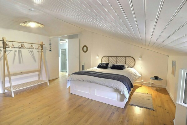 Quarto com cama, piso de madeira, guarda-roupa e luminária pendente.