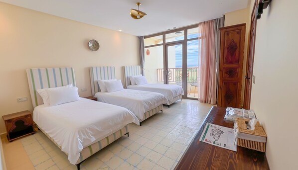 A hotel room with two beds, a wooden desk, and a balcony with a view. - Vrbo Property (Tanger)
