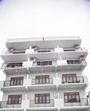 Un edificio de varios pisos con balcones, ventanas y unidades de aire acondicionado.