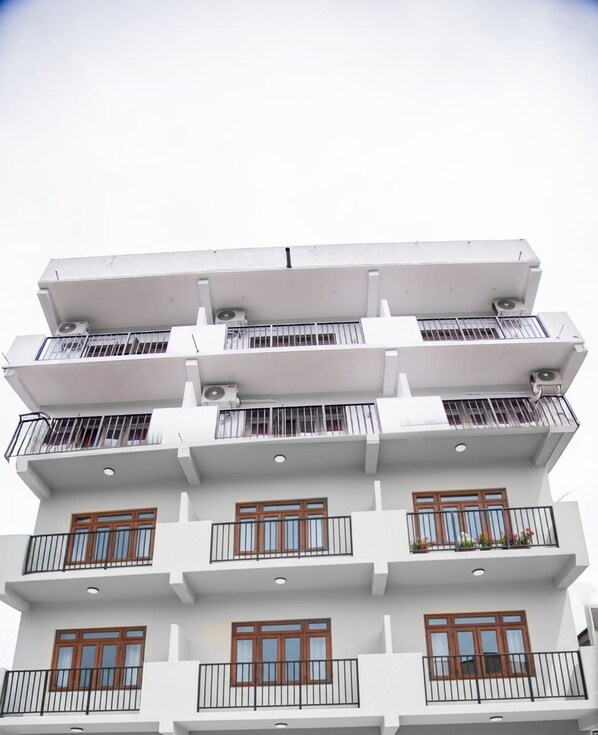 A multi-story building with balconies, windows, and air conditioning units.