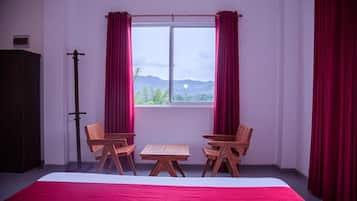 Una stanza con un letto, due sedie di legno, un tavolino e una finestra con tende.