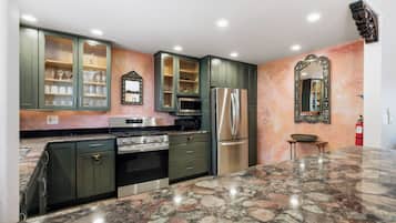A kitchen with granite countertops, stainless steel appliances, and green cabinetry.