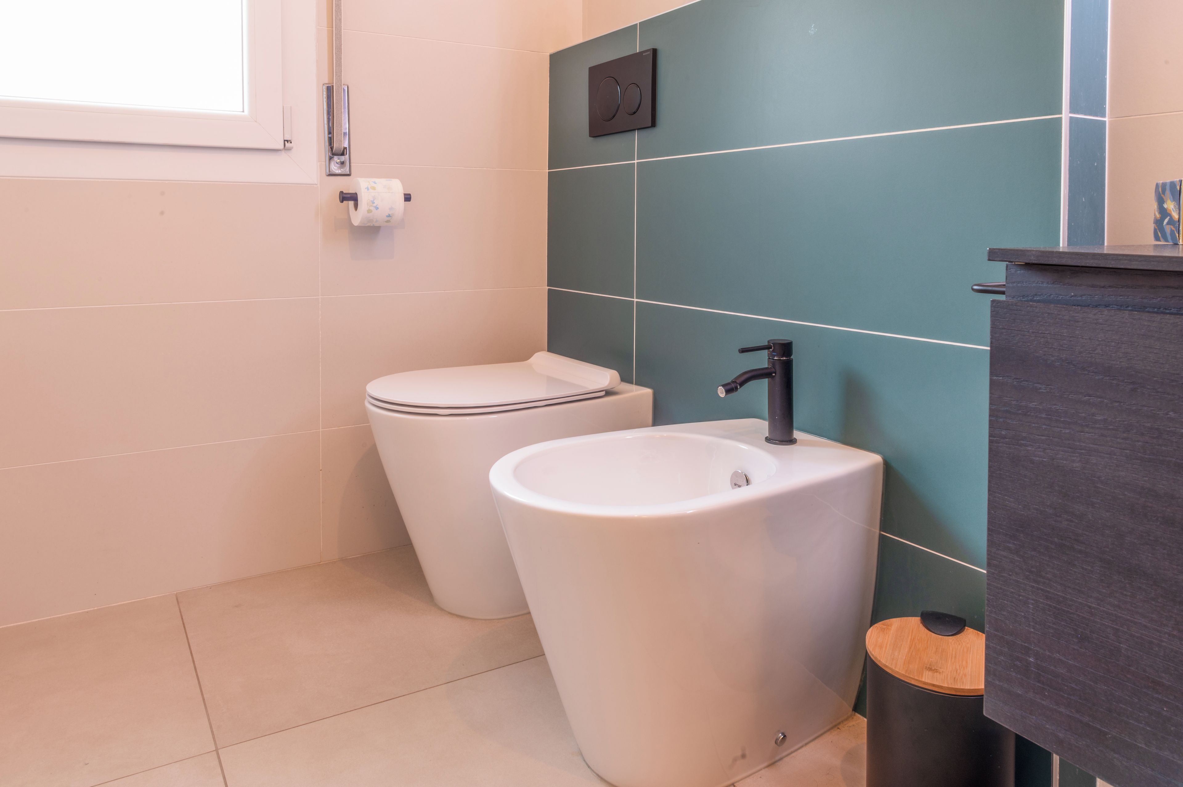 Un baño con inodoro, lavamanos y un cubo de basura.