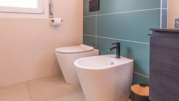 Un baño con inodoro, lavamanos y un cubo de basura.
