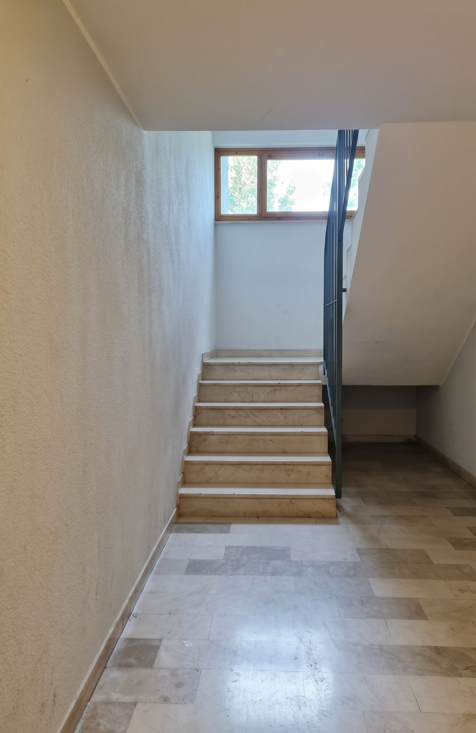 Un escalier avec des marches en bois, menant à un palier doté d’une fenêtre.