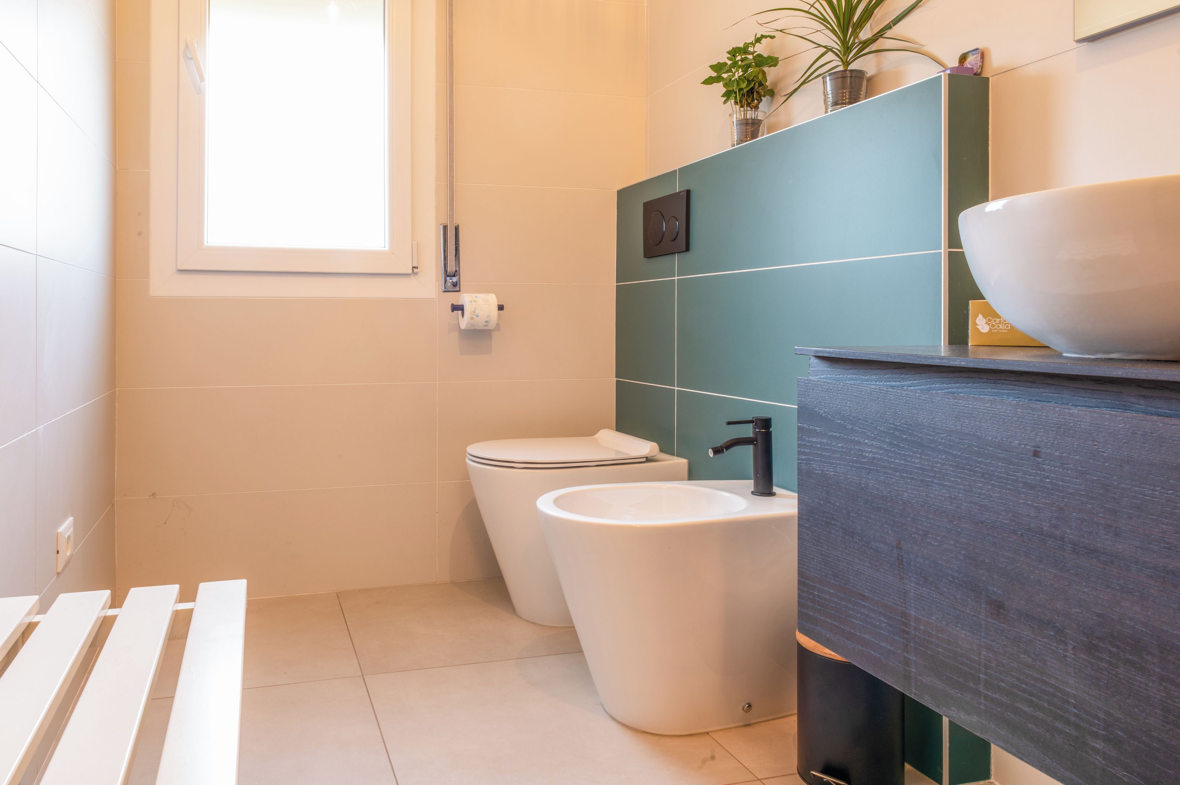 A modern bathroom with a toilet, bidet, and sink.