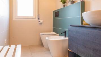 A modern bathroom with a toilet, bidet, and sink.
