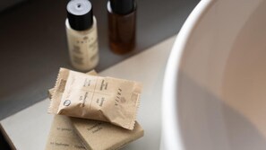 Une salle de bain avec une serviette, une bouteille et un récipient posés sur un comptoir.