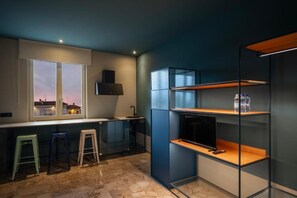 A modern kitchen with a built-in TV, a window with a city view, and a bar area with stools.