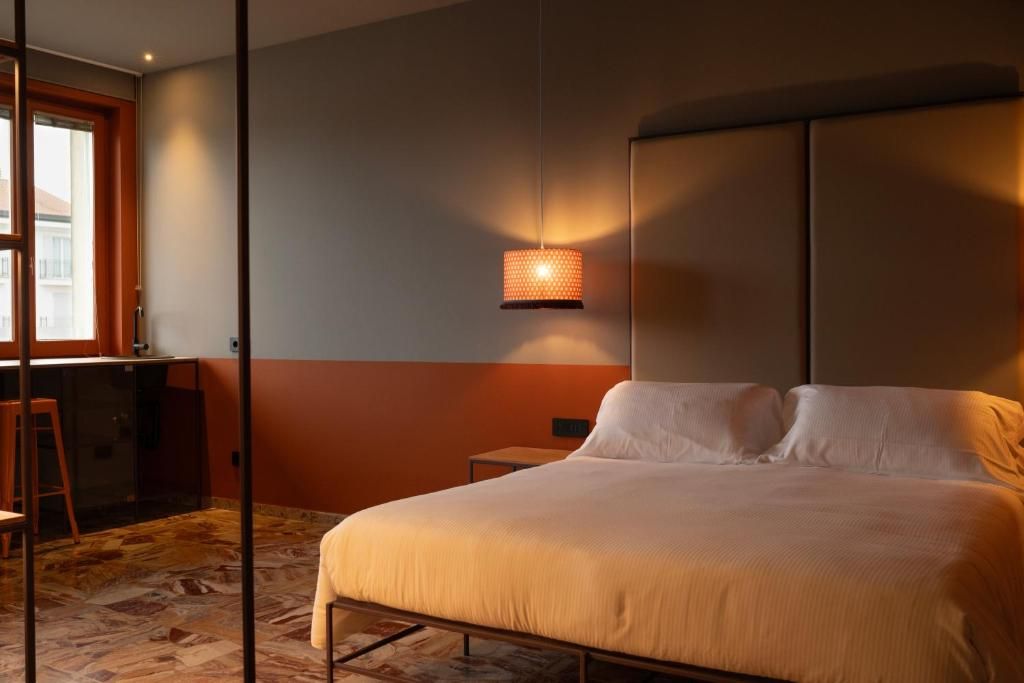 Un dormitorio con una cama, una mesita de noche, una lámpara y una ventana.