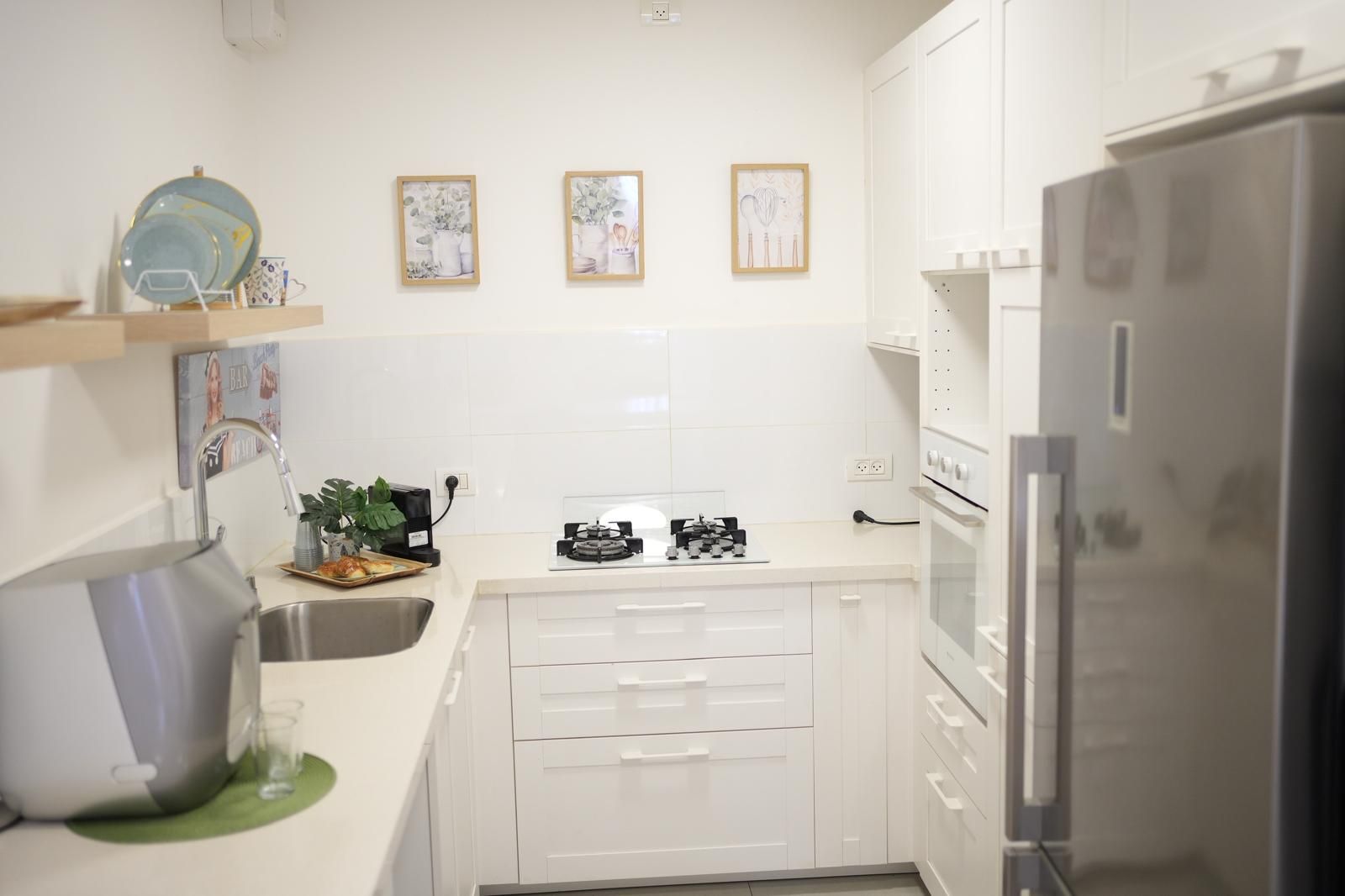 Una cocina moderna con armarios blancos, un refrigerador de acero inoxidable y una estufa a gas.