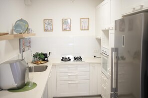 Een moderne keuken met witte kasten, een roestvrijstalen koelkast en een gasfornuis.