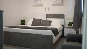 Een moderne slaapkamer met een groot bed, nachtkastjes en een bijzetmeubel.