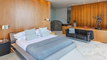Moderni hotellihuone, jossa on suuri sänky, oleskelualue ja vastaanottotiski.