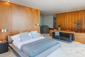 Ein modernes Hotelzimmer mit einem großen Bett, einer Sitzecke und einer Rezeption.