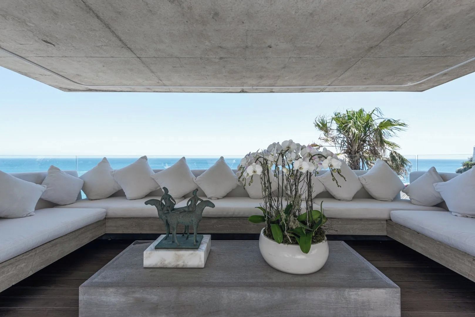 Un espace de détente moderne avec un canapé et une table basse, une sculpture décorative et un pot d’orchidée.