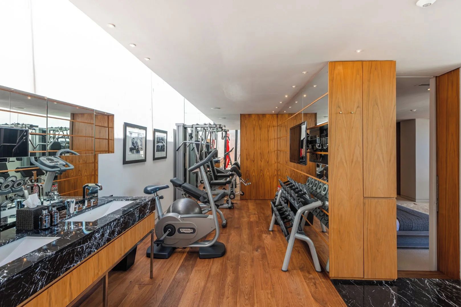 Une salle de sport moderne équipée de machines de cardio, d’appareils de musculation et d’un grand miroir.