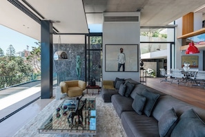 Un salon moderne avec un grand canapé, une table basse agrémentée d’objets décoratifs, un tableau et une vue sur l’extérieur.