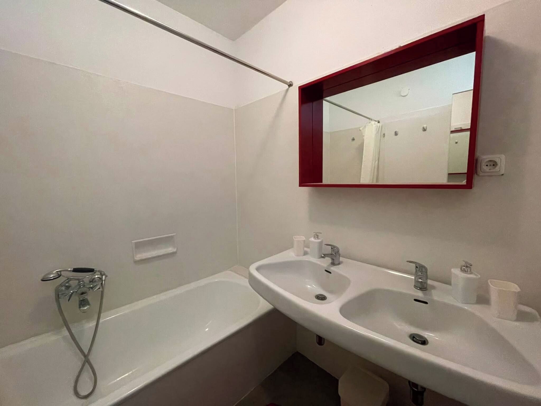 A bathroom with a bathtub, two sinks, a mirror, and a shower.
