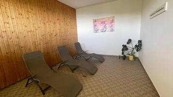 Ein Zimmer mit drei Liegesesseln, einer Holzwand, einem Blumenbild und einem Blumentopf.