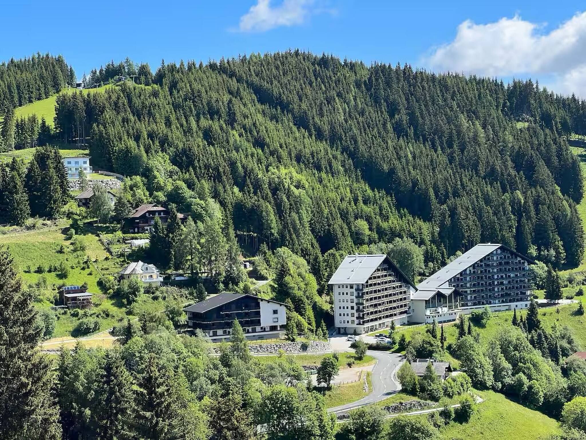A mountainous area with a cluster of buildings, including a large hotel with multiple floors and a smaller building nearby.