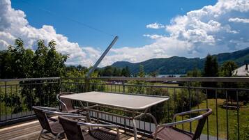 Ein Balkon mit Tisch und Stühlen, der auf einen See und Berge blickt.