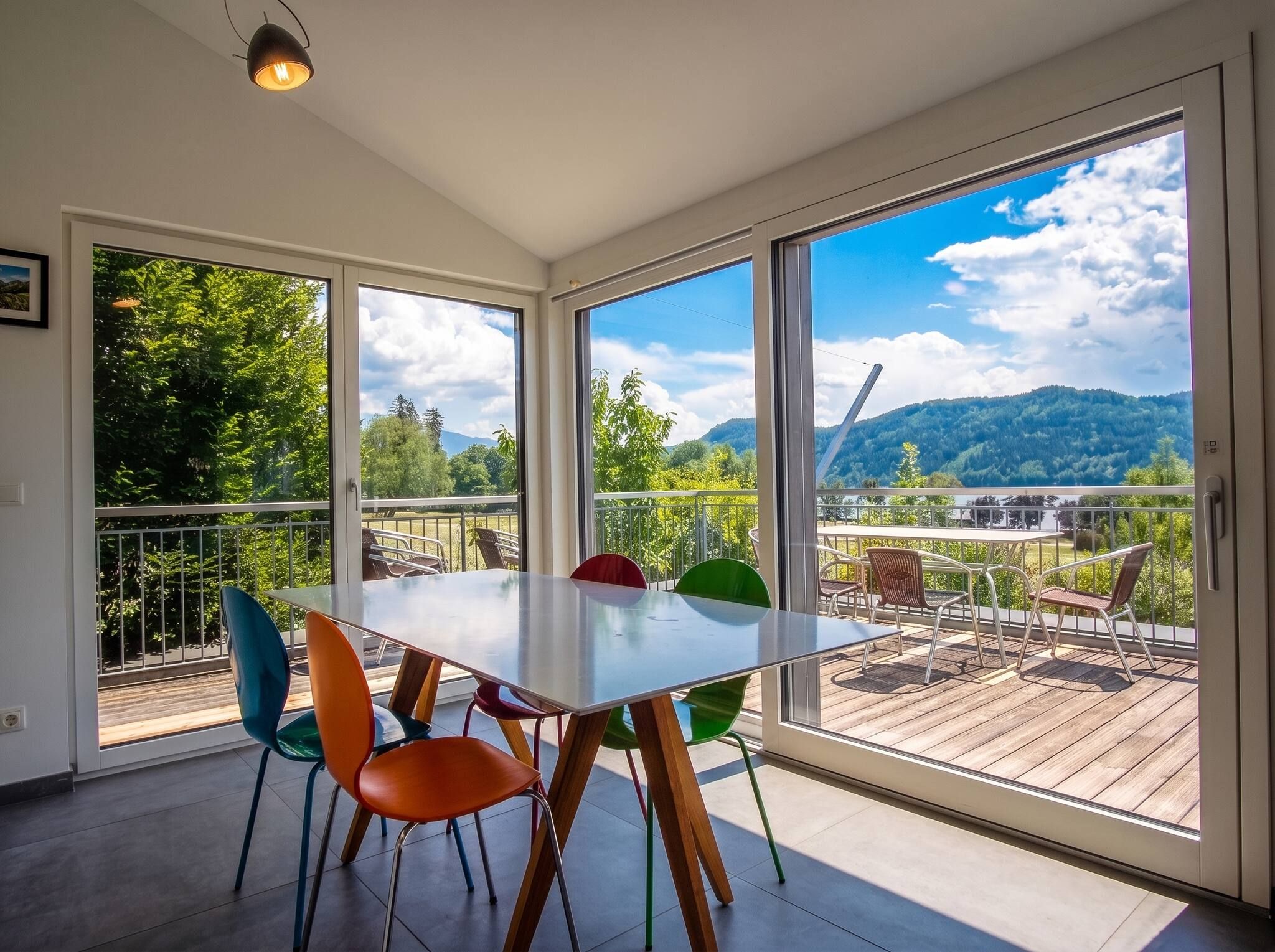 A dining area with a table and chairs, large windows, and a view of a forest and mountains.