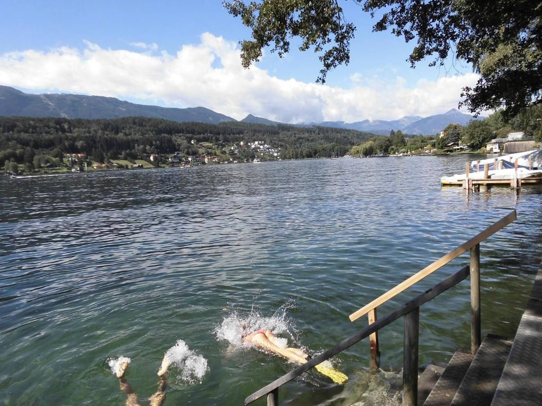 Ein See mit einer Holzsteganlage und einem Schwimmer im Wasser.