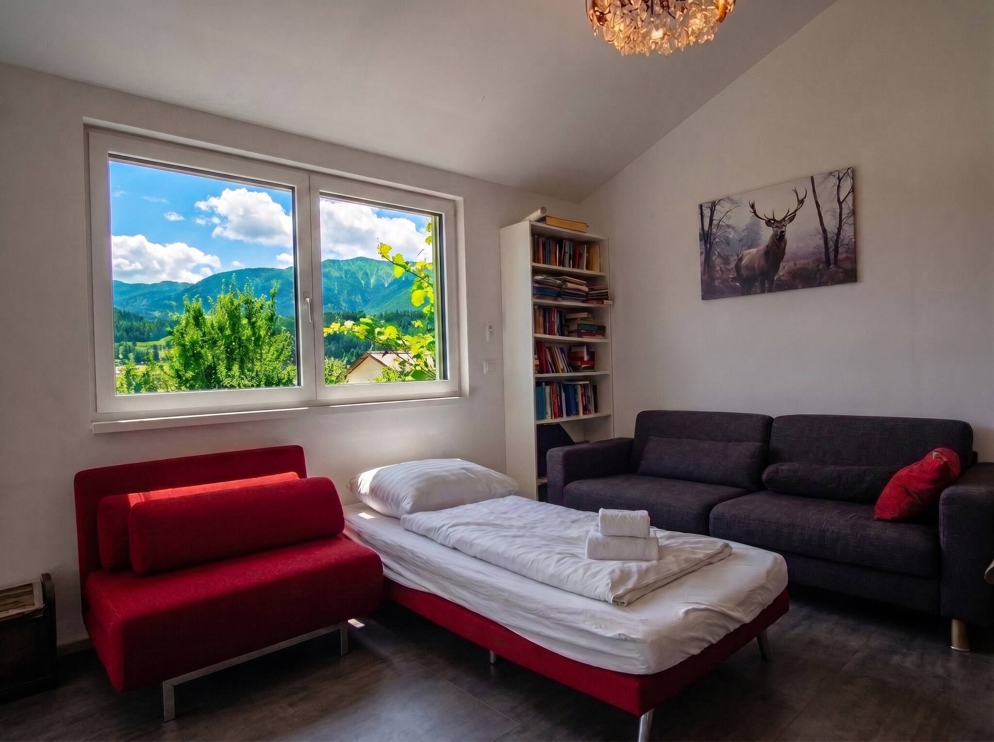 Een slaapkamer met een bed, een rode bank, een donkere bank, een boekenkast en een schilderij van een eland.