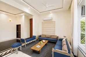 A modern living room with a sofa set, a coffee table, and a ceiling fan. - Alaya Stays Leora Amar Villa 6BHK (Udaipur)