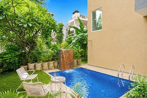 A swimming pool with a glass edge, surrounded by lush greenery and a white chair. - Alaya Stays Leora Amar Villa 6BHK (Udaipur)