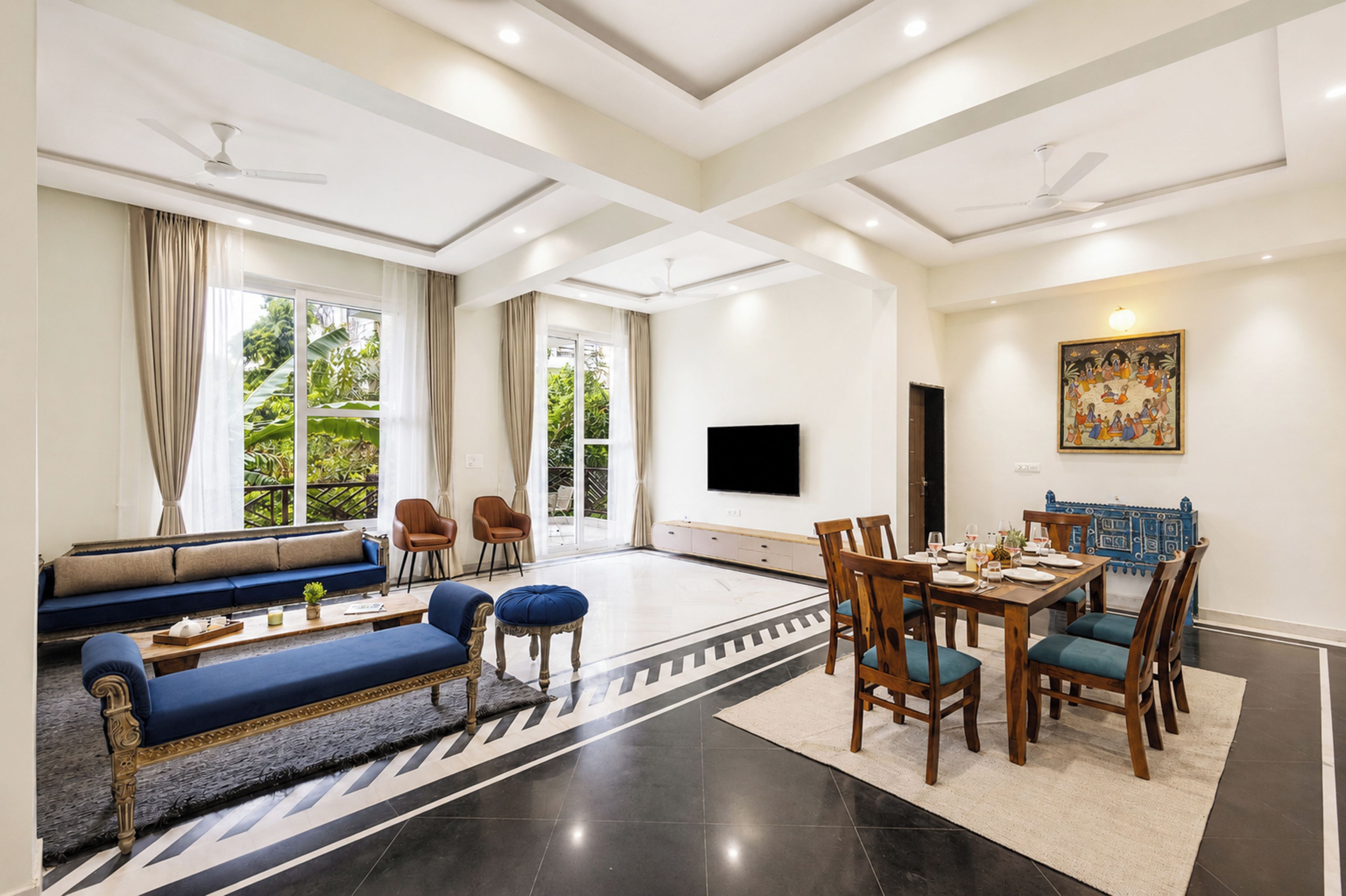 Amplia sala de estar con sofá, mesa de comedor, sillas y televisor de pantalla plana.