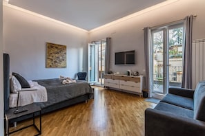 A modern bedroom with a bed, a desk, a TV, and a balcony with a view. - Copy of President Gardens (Rome)