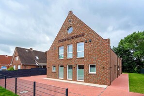 Ein Wohngebäude mit Ziegelverkleidung, mehreren Fenstern und blauem Himmel.