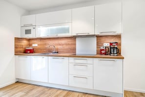 Eine moderne Küche mit weißen Schränken, einer Holz Arbeitsplatte, einer Mikrowelle, einer Kaffeemaschine und einem Toaster.