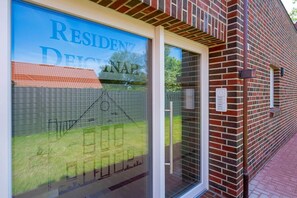 A residential building with a brick facade, a glass door entrance, and a clear view of the surrounding area. - Vacation Rental on Langeoog (Norden)