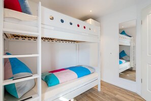 A bunk bed room with a white color scheme, wooden flooring, and a mirror on the wall. - Spiekeroog Vacation Rental (Norden)